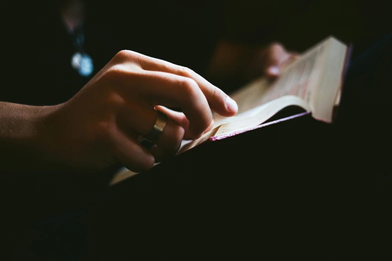 a person holding an open book on a black background