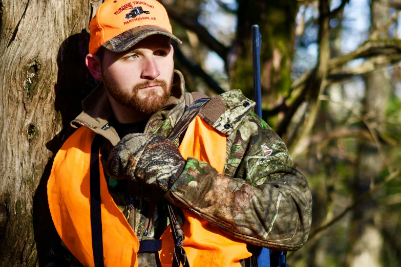 a man with orange vest next to tree