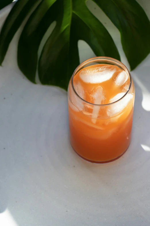 a small glass with liquid sitting on top of a white table