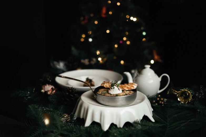 a plate with soup and two bowls next to a christmas tree