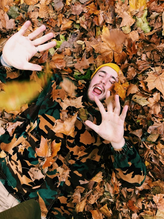 a person lying on the ground surrounded by autumn leaves