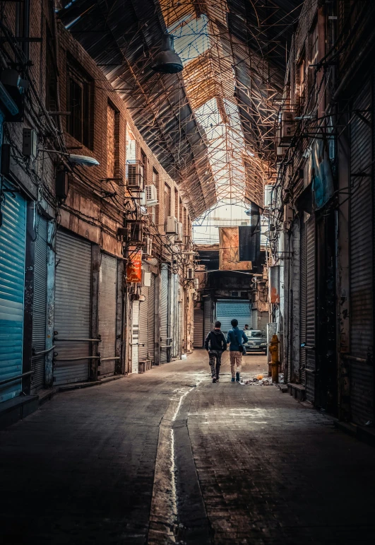 two people walking down an alley between old brick buildings