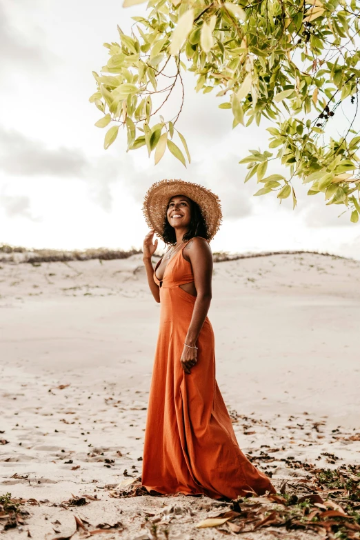 a woman in an orange dress wearing a straw hat