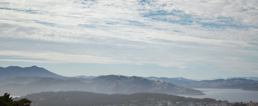 a hill view overlooking a body of water, mountains and small town