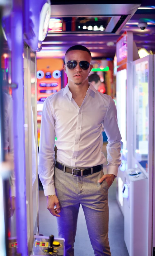 a man is standing by a toy machine and wearing sunglasses