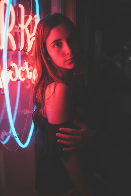 girl standing near a neon sign holding a man in her arms