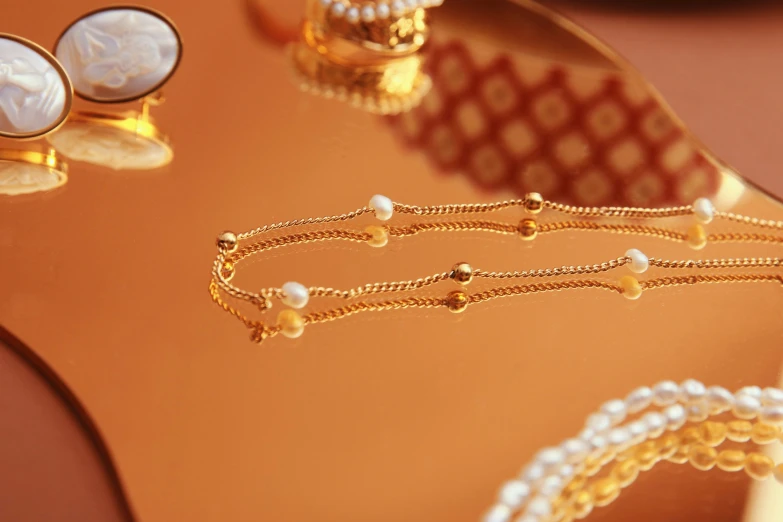 some golden jewellery on a table near some brooches