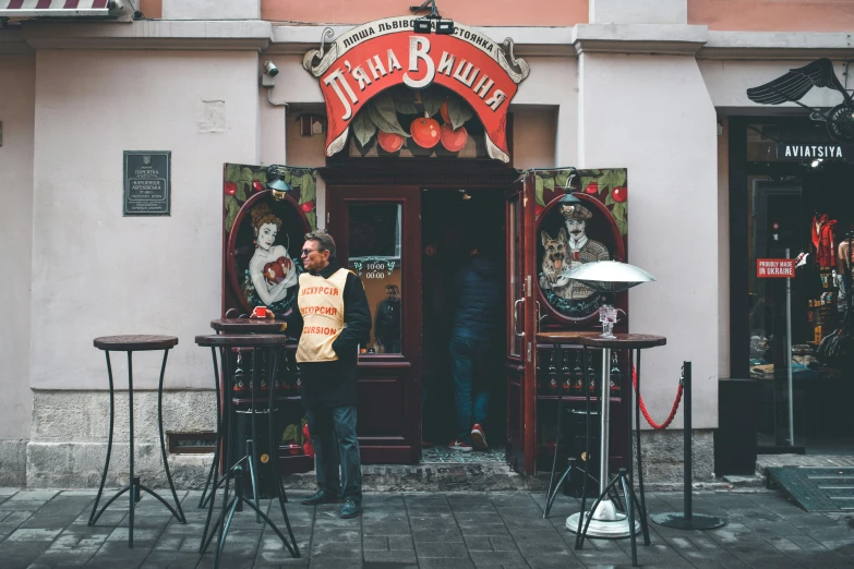 a man in front of a restaurant holding an orange cup