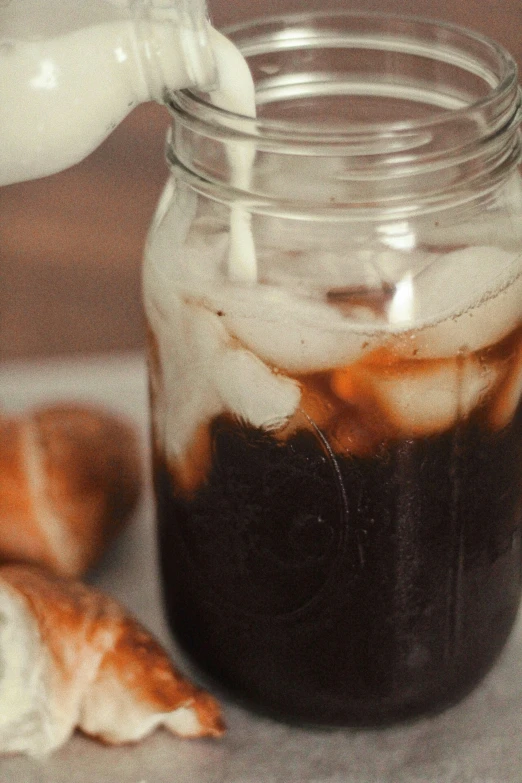 an iced drink in a jar sitting next to a broken pastry