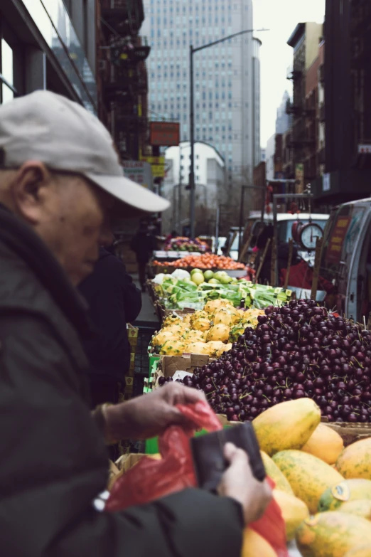 a man in grey hat standing by fruit and vegetables