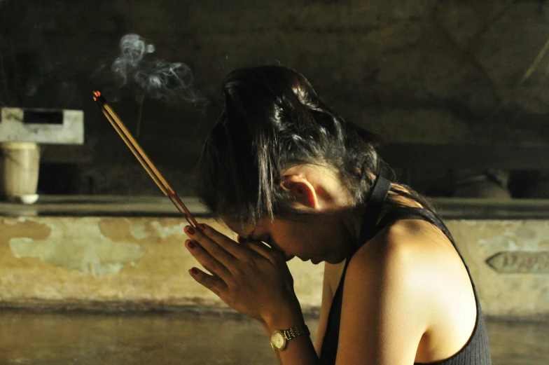 a woman sitting on the ground with a pipe sticking out of her mouth