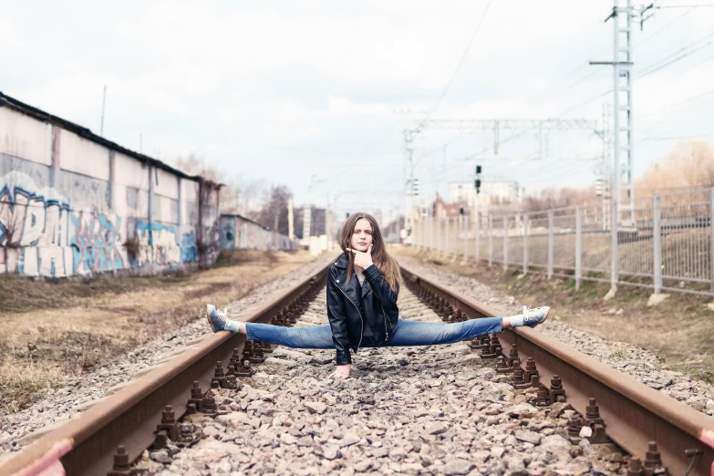 a woman posing with her arms outstretched sitting on the tracks