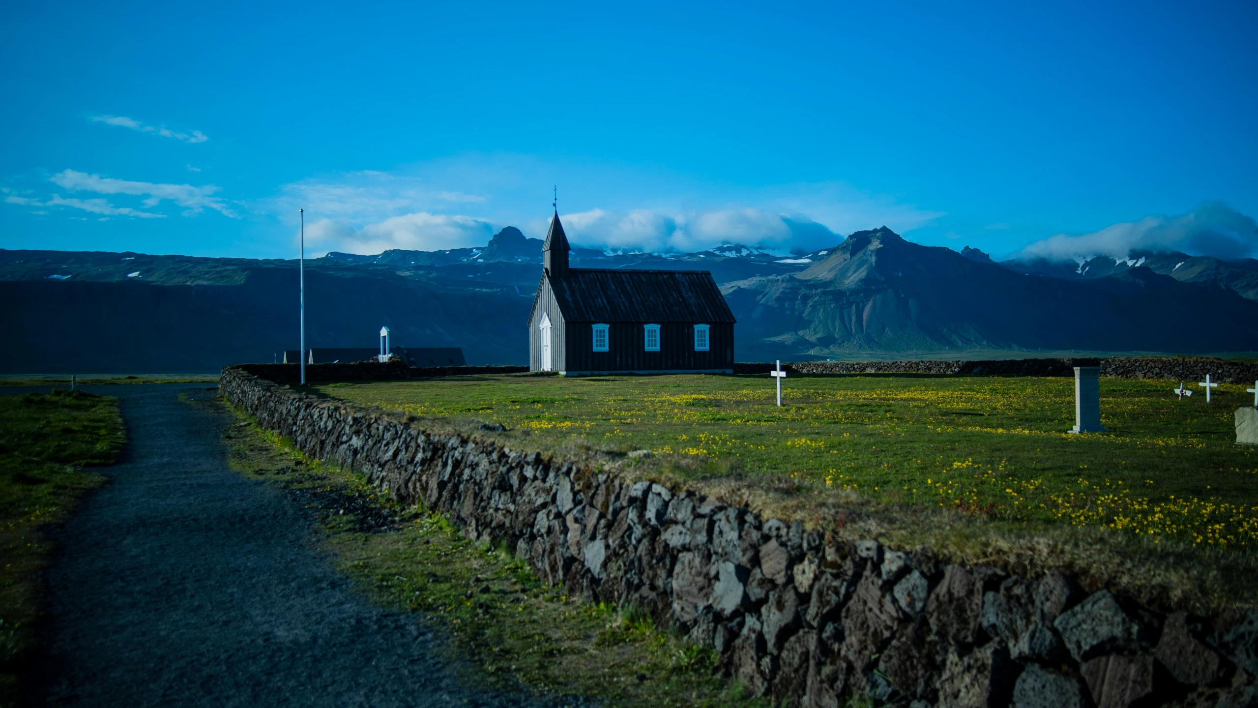 a church stands with tall mountains in the background