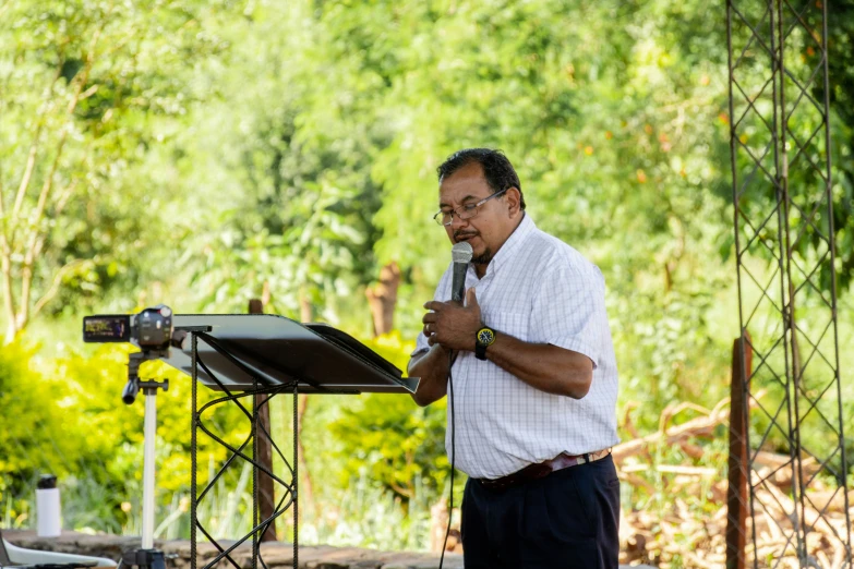 a man stands at a microphone with an outdoor stage