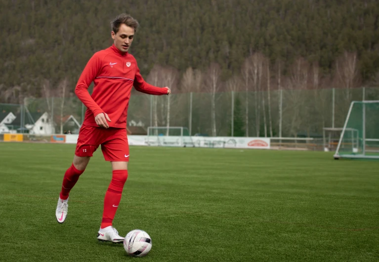 a man in red is kicking a soccer ball