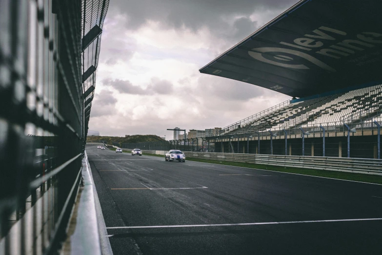 cars driving down a track in an asphalt covered area