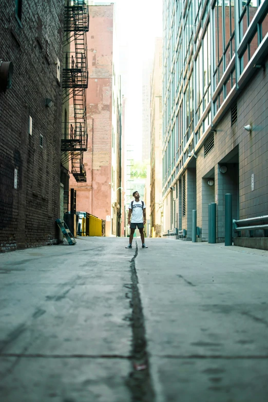 a man wearing a white shirt walking down an alley