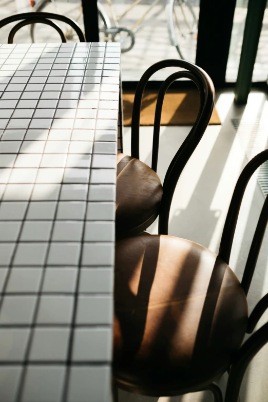 chairs are at a restaurant counter with their shadows on the table