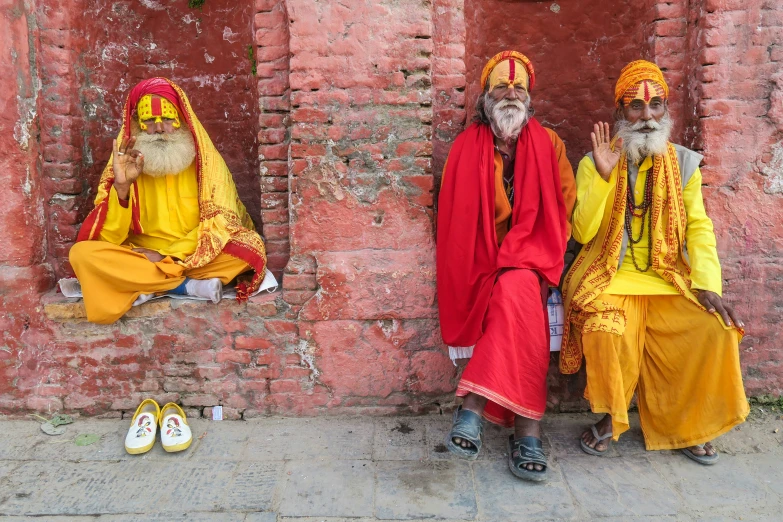 two men wearing colorful attire next to red brick building