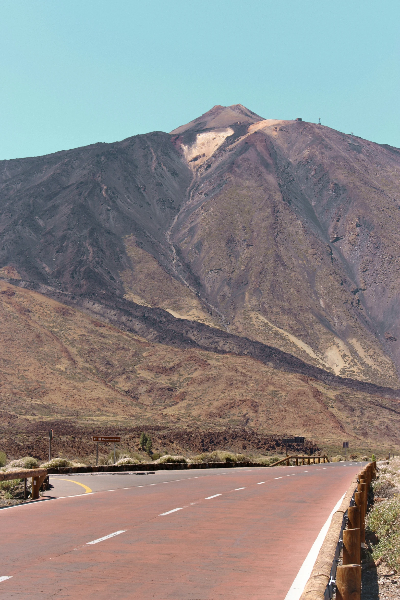 an empty roadway with an animal fence and mountains behind it