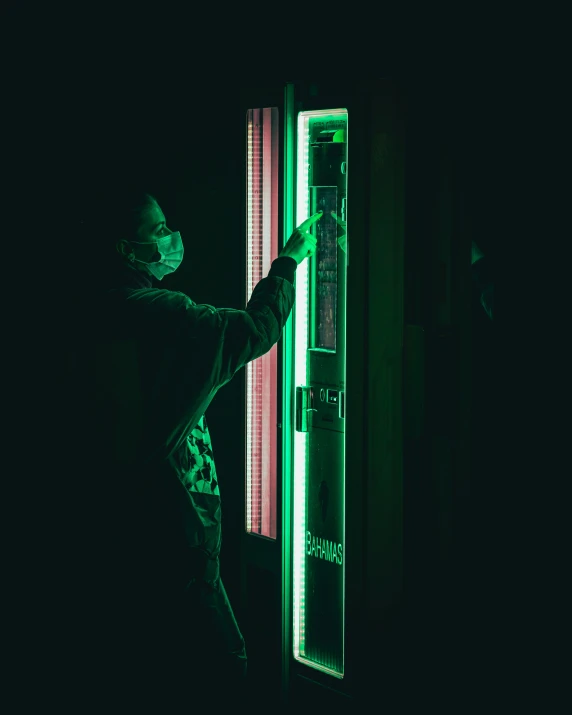 person in dark room holding onto door as light emits from