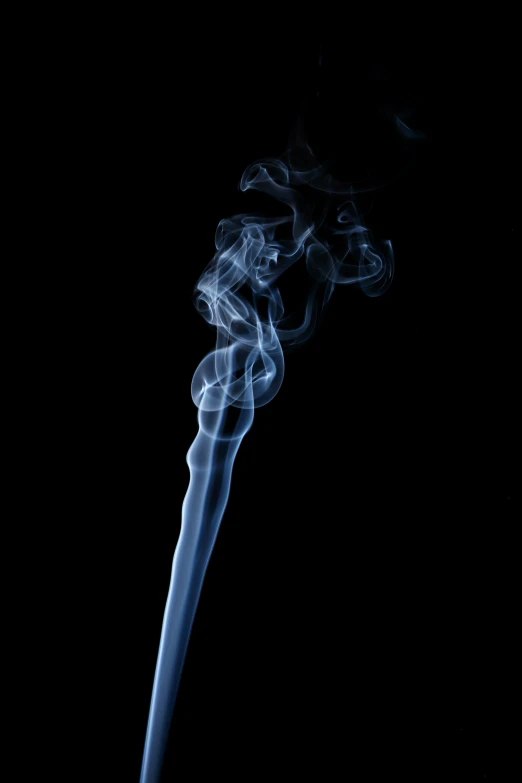 a smoking cigarette is in the dark with smoke coming out