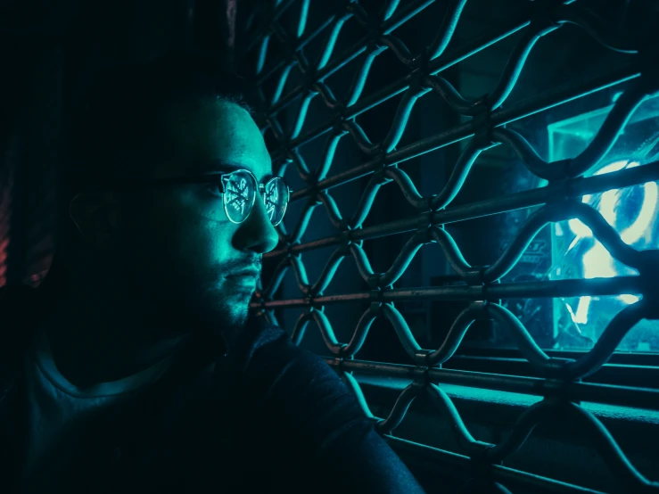 a man with glasses and metal wire in the dark