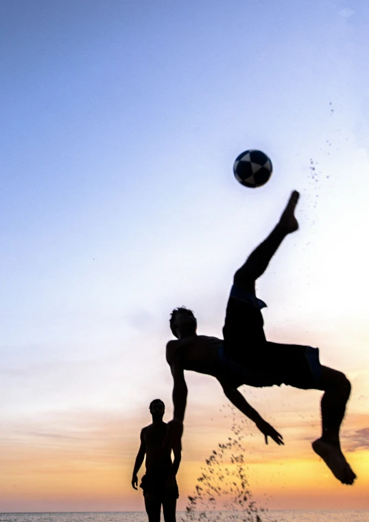 the young man is jumping to catch the ball at sunset