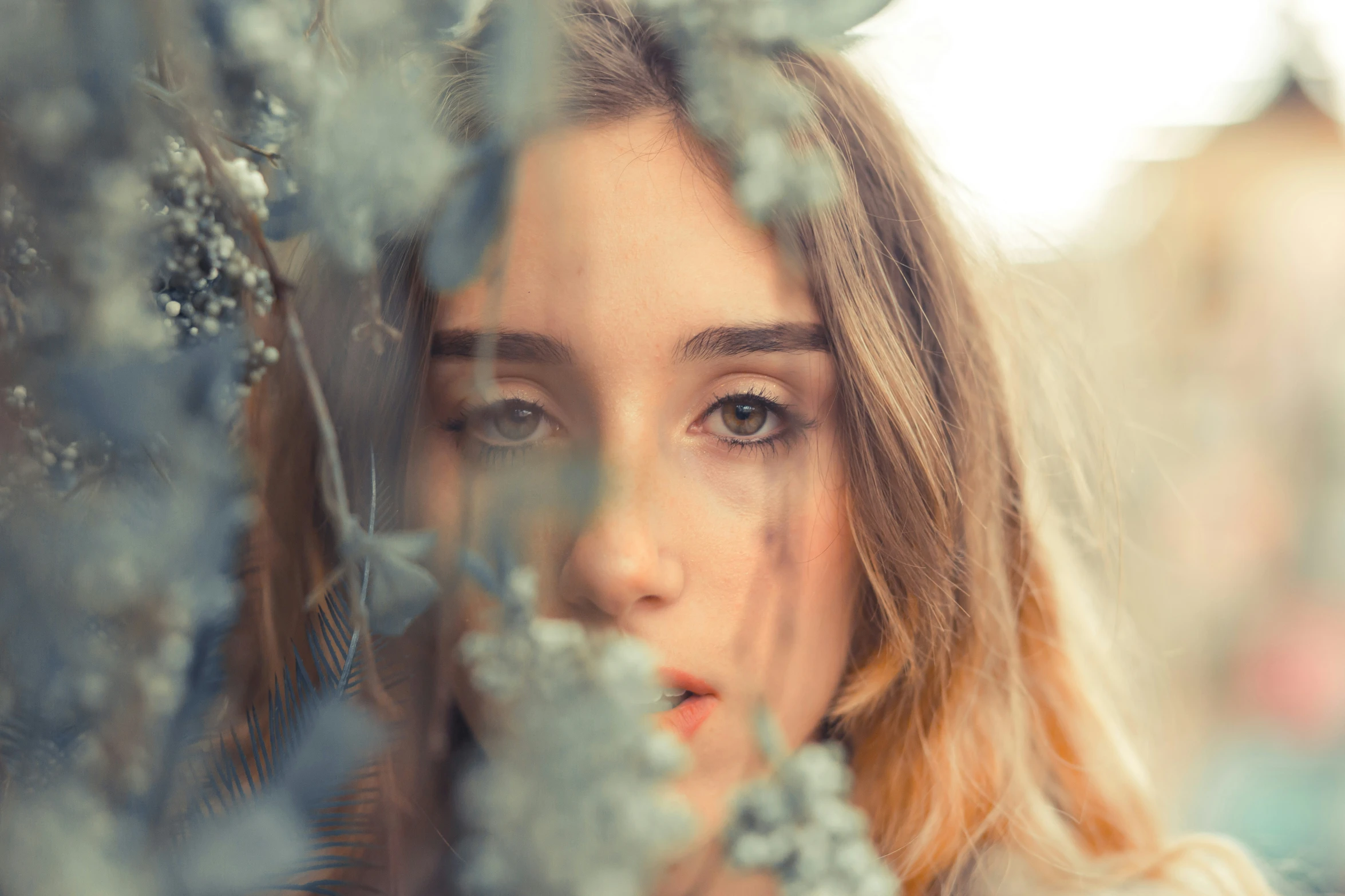 a woman with very pretty blue eyes standing under a tree