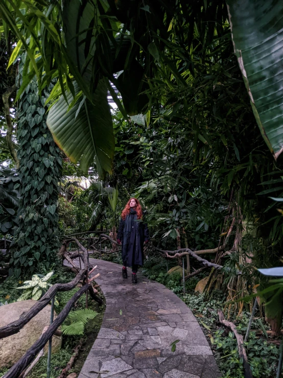 a woman walking down a stone pathway with lots of greenery