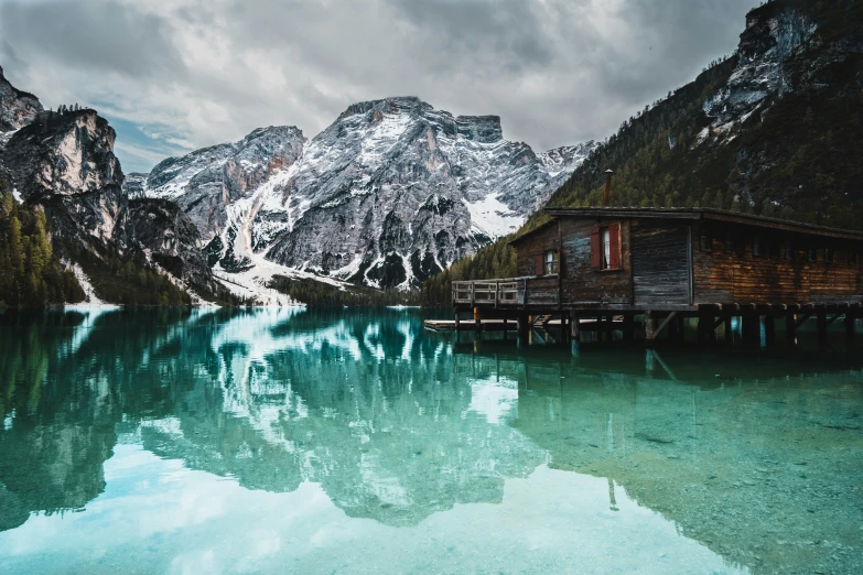 a wooden cabin by a large mountain lake