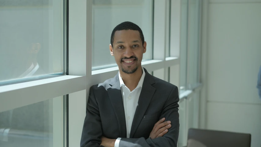 a man in a business suit leaning against a window