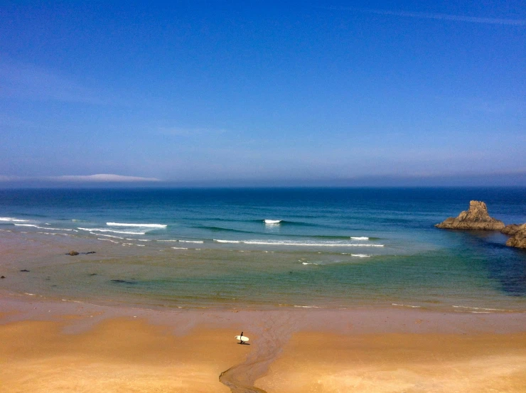 a person stands on the beach with their surf board