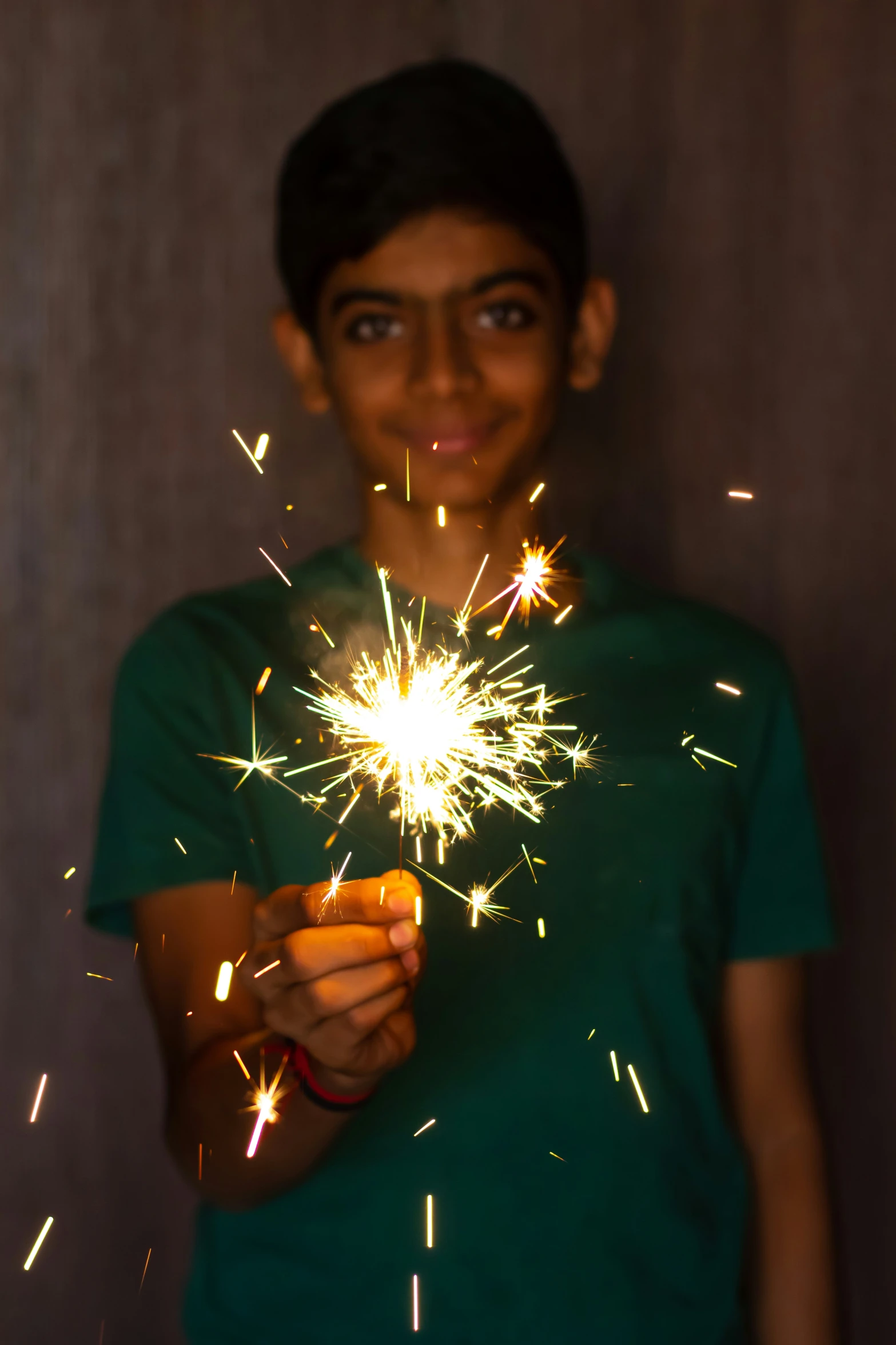 a boy holding soing in his hand while standing next to a wall