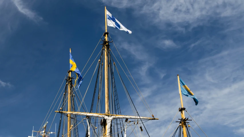 a ship mast with sails and two flags