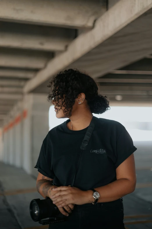 woman standing on the side of an overpass holding a camera