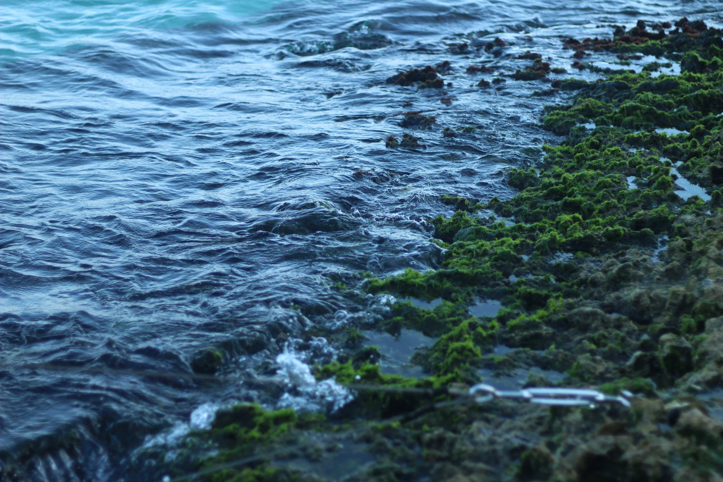 waves crashing over the shoreline with rocks on shore