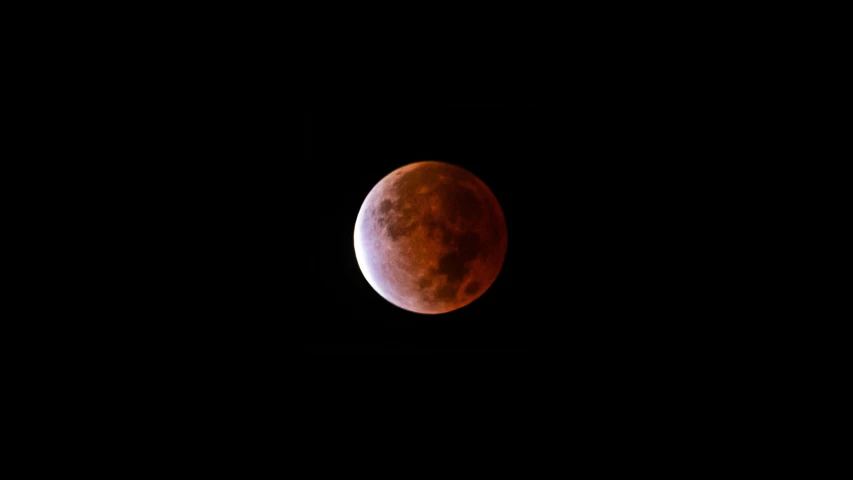 a red moon is in the dark sky