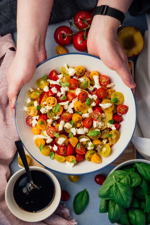 someone's hands holding a plate full of sliced heir tomatoes