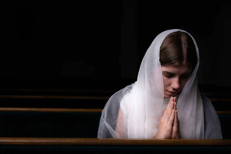 a girl wearing a white veil sitting at a table