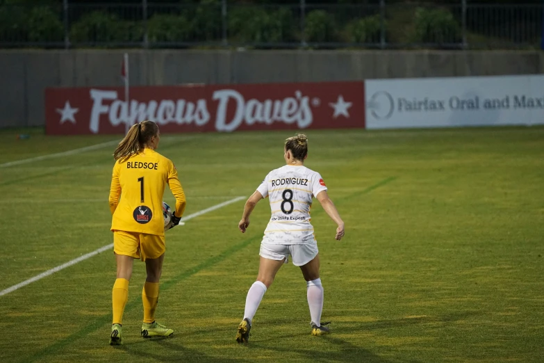 two girls are playing soccer on a field