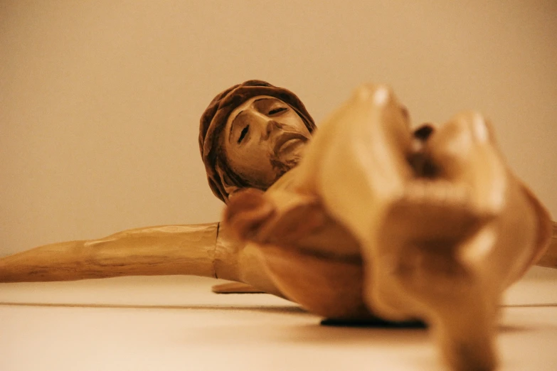 a wooden sculpture of a man laying on the floor