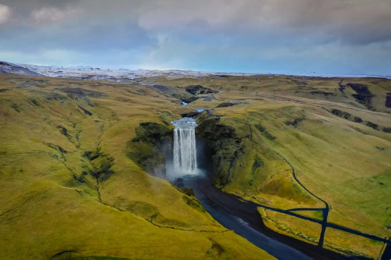 a very tall waterfall sitting on the side of a lush green hill