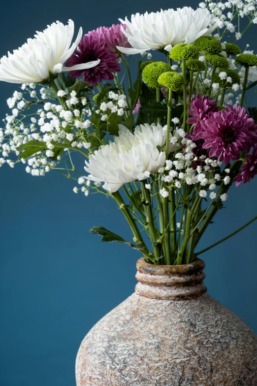 some pretty purple and white flowers in a stone vase