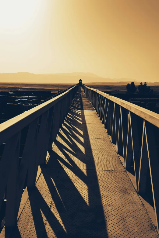 a person walking along a bridge into the sunset