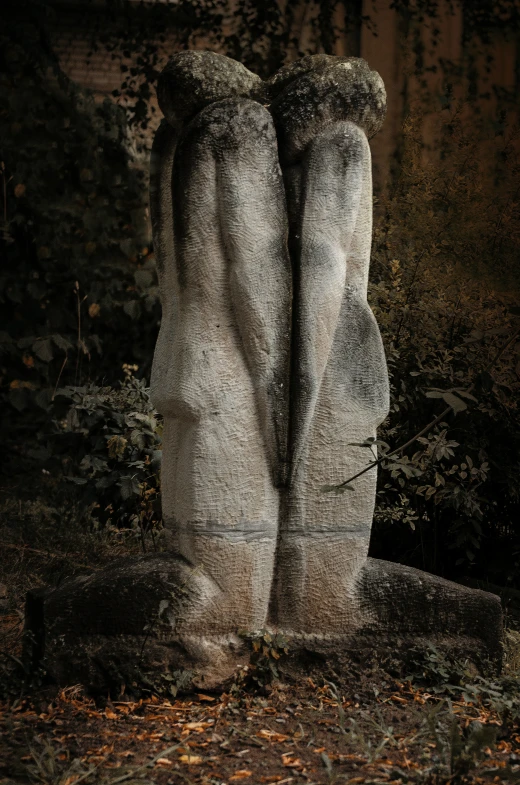 two gray statues sitting on top of grass