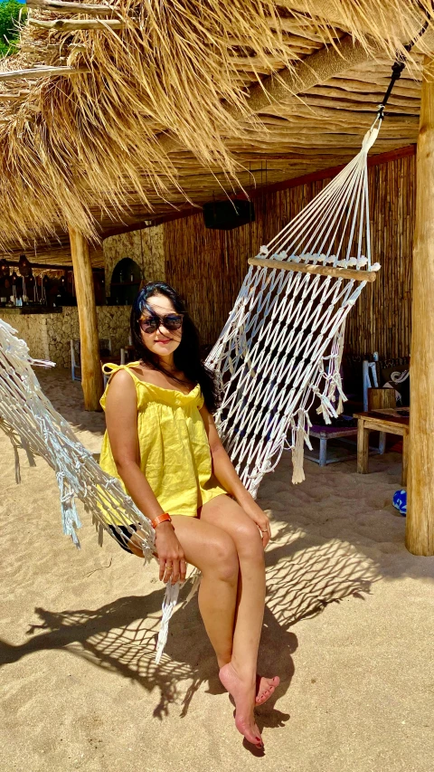 a young woman in a yellow top is sitting on a hammock