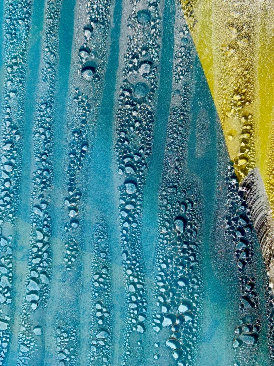 a blue window covered in raindrops next to a street