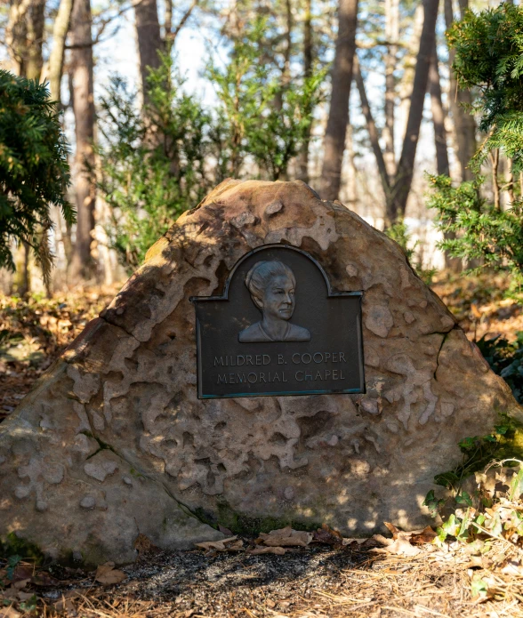 an outdoor memorial stone sits in front of trees