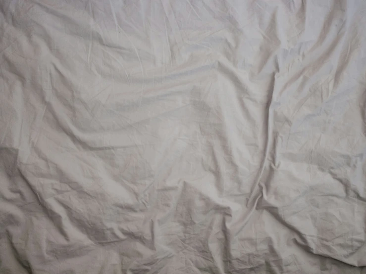 a grey blanket covering a bed that is made